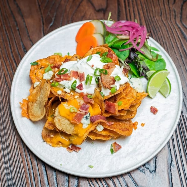 Loaded potato chips with melted cheese, bacon, sour cream, chives, and a side salad.